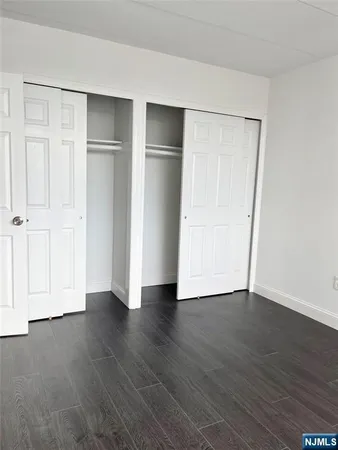 a view of an empty room with wooden floor and closet area