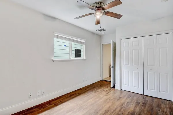an empty room with wooden floor chandelier fan and closet area