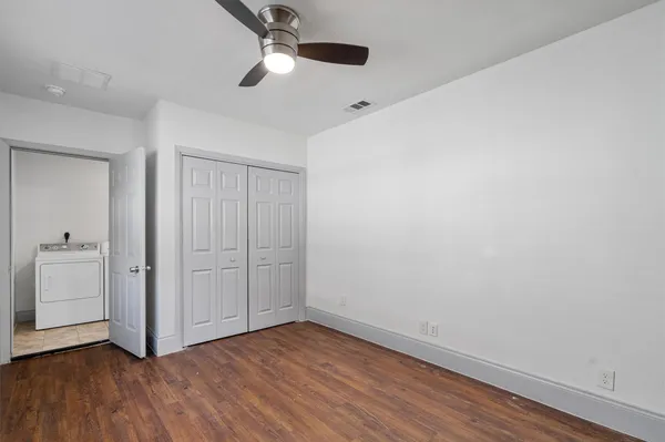 an empty room with wooden floor cabinet and windows