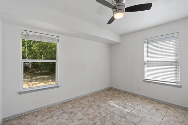 an empty room with a window and a fan