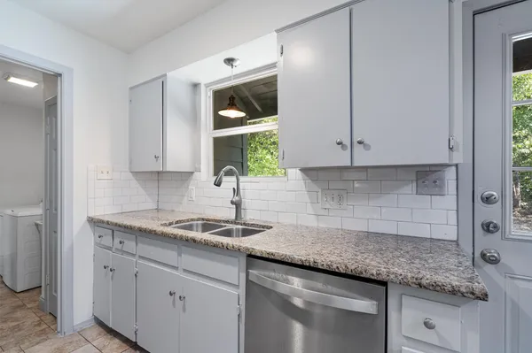 a kitchen with granite countertop white cabinets and a sink