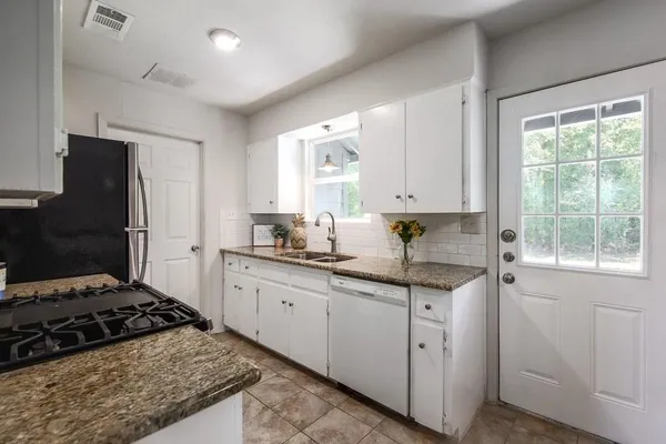 a kitchen with white cabinets and appliances