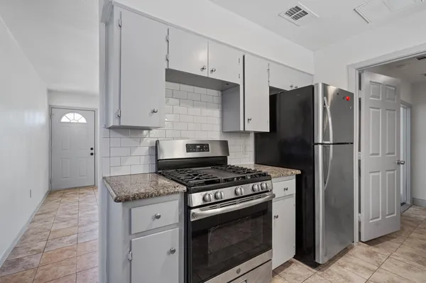 a kitchen with granite countertop a stove sink and refrigerator