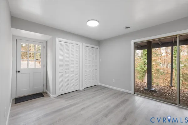 an empty room with wooden floor and windows