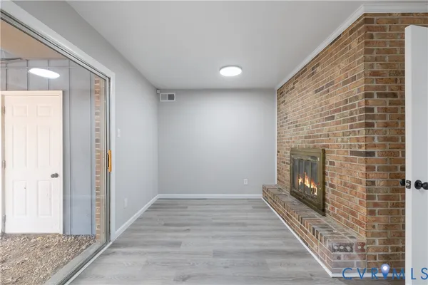 a view of an empty room with wooden floor and a fireplace