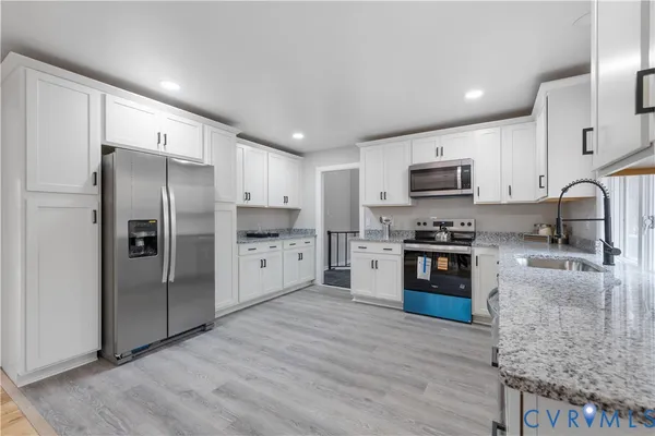 a kitchen with stainless steel appliances granite countertop a refrigerator stove and sink