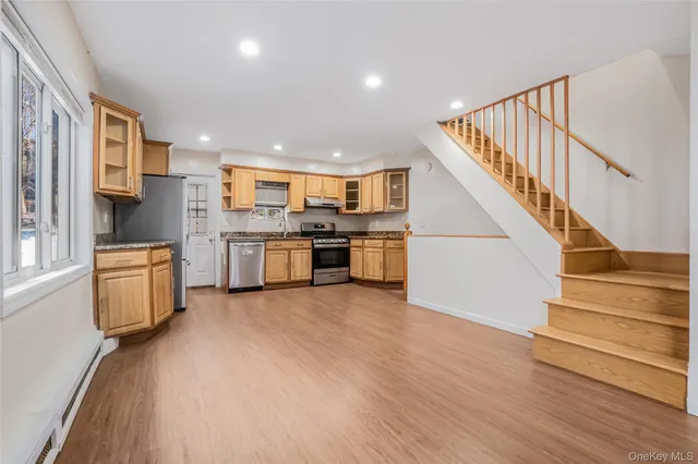 a view of kitchen with stainless steel appliances kitchen island wooden floor and staircase