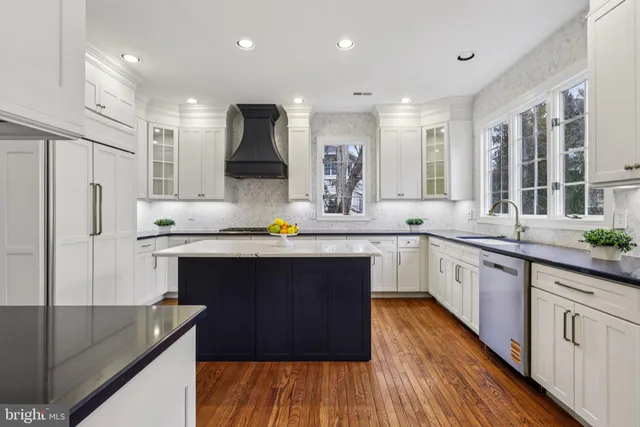 a kitchen with stainless steel appliances granite countertop a refrigerator a stove and white cabinets with wooden floor