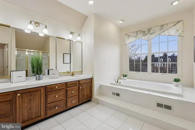 a view of a white house with a yard plants and large tree