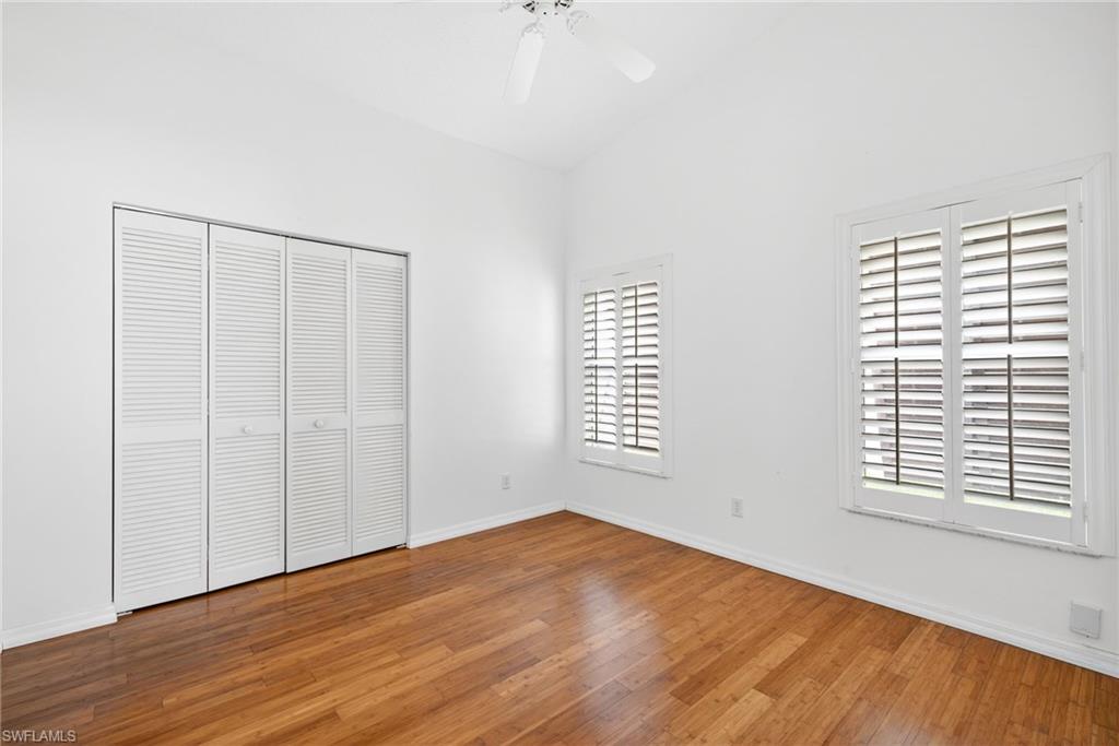 7071 Mill Pond Circle Naples, FL 34109 - Photo 14 of 24 Unfurnished bedroom featuring a closet, hardwood / wood-style flooring, a ceiling fan, and high vaulted ceiling