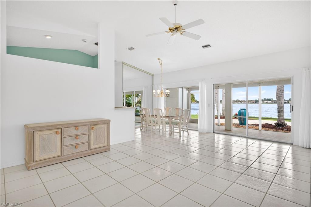 7071 Mill Pond Circle Naples, FL 34109 - Photo 4 of 24 Spare room featuring lofted ceiling, a water view, a ceiling fan, a chandelier, and light tile patterned flooring