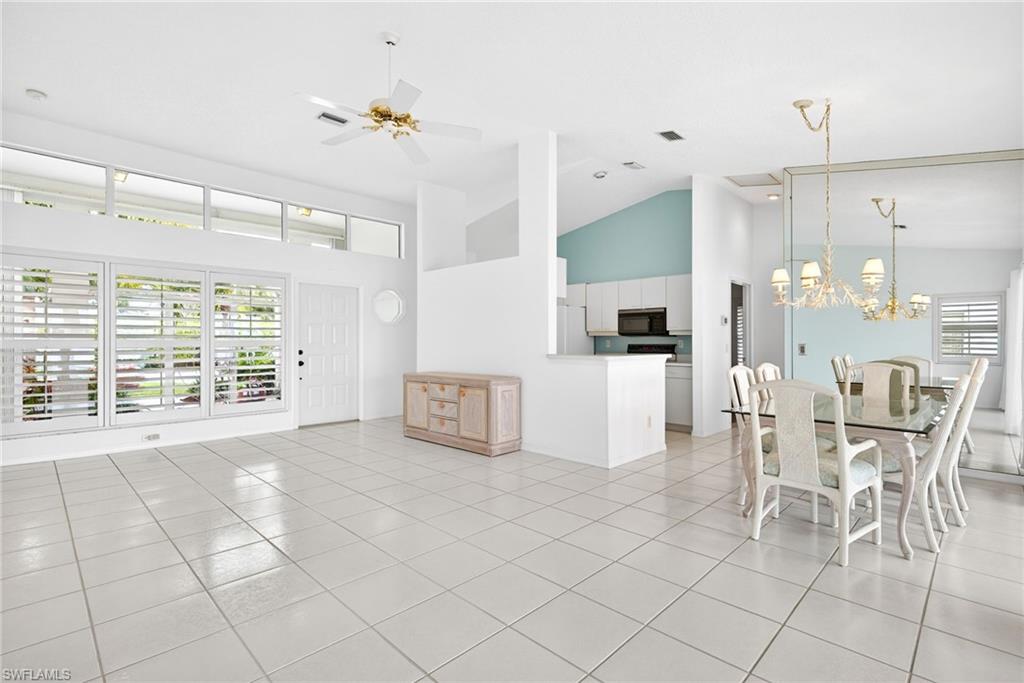 7071 Mill Pond Circle Naples, FL 34109 - Photo 6 of 24 Dining area with high vaulted ceiling, a ceiling fan, a chandelier, healthy amount of natural light, and light tile patterned flooring