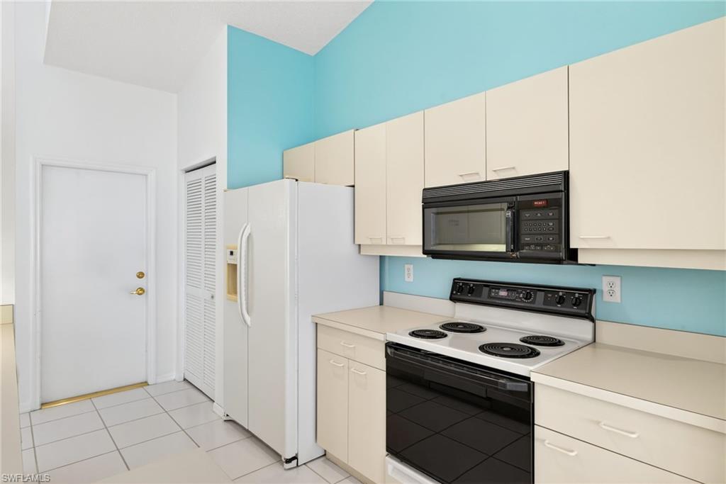7071 Mill Pond Circle Naples, FL 34109 - Photo 9 of 24 Kitchen with electric range oven, light countertops, black microwave, and light tile patterned floors