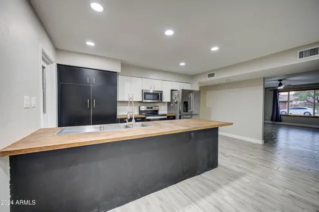 a large kitchen with stainless steel appliances a large counter top a stove and a refrigerator