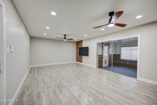 a view of empty room with wooden floor and ceiling fan