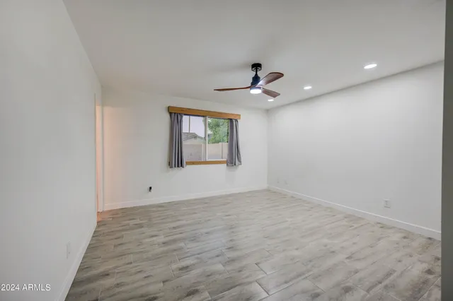 an empty room with a window and a ceiling fan