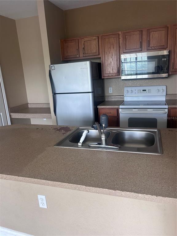 8213 Claire Ann Drive, Unit 203 Orlando, FL 32825 - Photo 4 of 9 a kitchen with granite countertop a refrigerator and a stove top oven