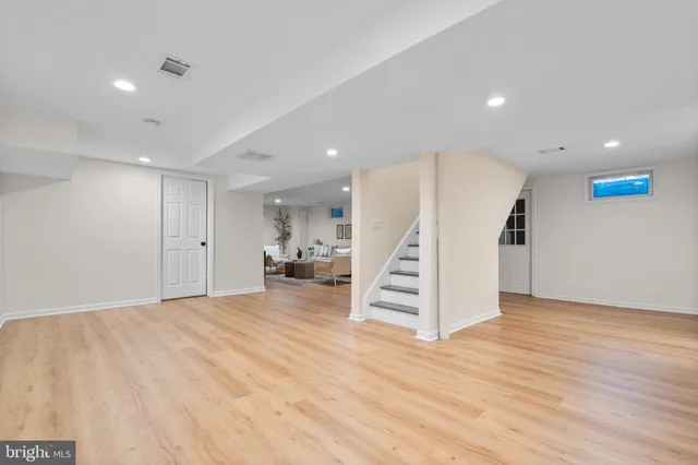a view of an empty room with wooden floor and stairs