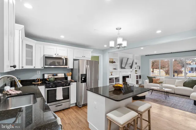 a kitchen with stainless steel appliances granite countertop a stove top oven a sink dishwasher a dining table and chairs with wooden floor