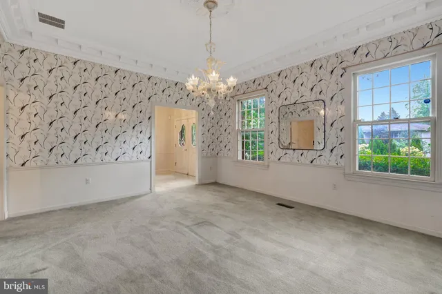 a view of an empty room with a windows and chandelier