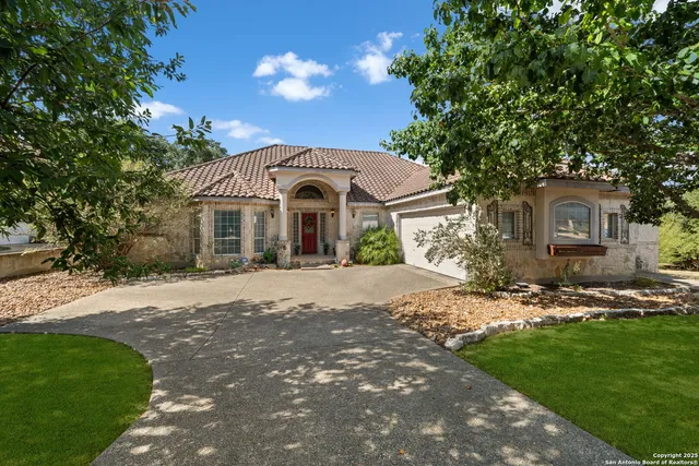 a front view of a house with a garden and trees