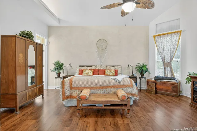 a bedroom with wooden floor and large windows