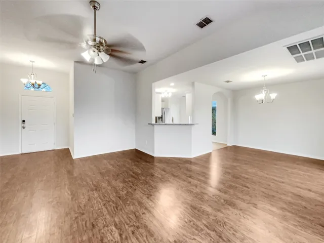 a view of empty room with wooden floor and kitchen view