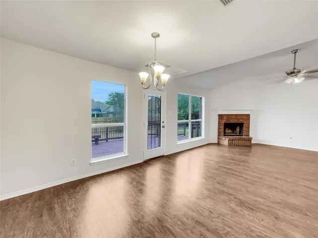 an empty room with wooden floor a fireplace and window