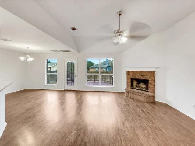 a view of an empty room with wooden floor fireplace and a window