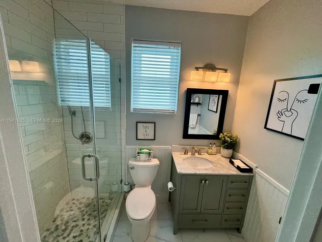 a bathroom with a sink a toilet a mirror and shower