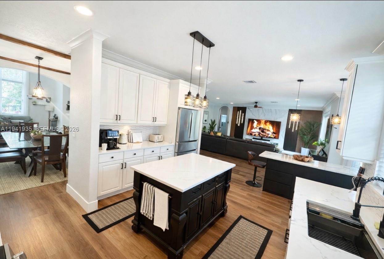12917 Southwest 23rd Street Miramar, FL 33027 - Photo 5 of 47 a large kitchen with sink a stove a refrigerator and a dining table with wooden floor