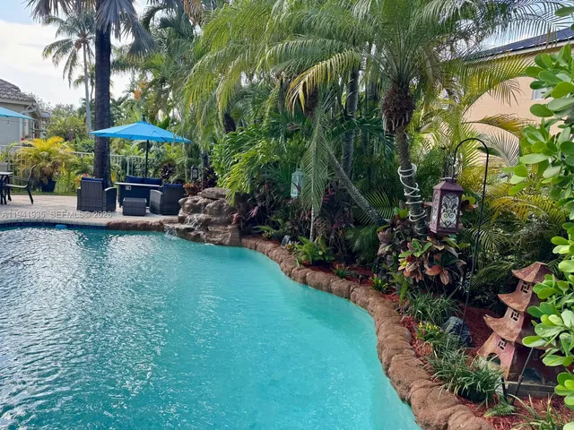 a view of a backyard with plants and a table and chairs under an umbrella
