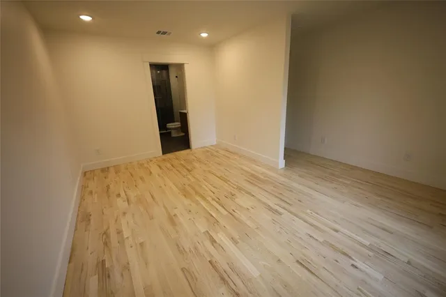 an empty room with wooden floor and a bathroom