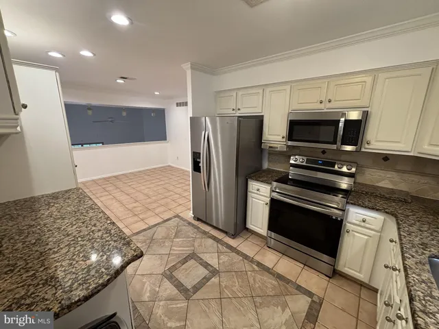 a kitchen with stainless steel appliances kitchen island granite countertop a refrigerator and a stove top oven