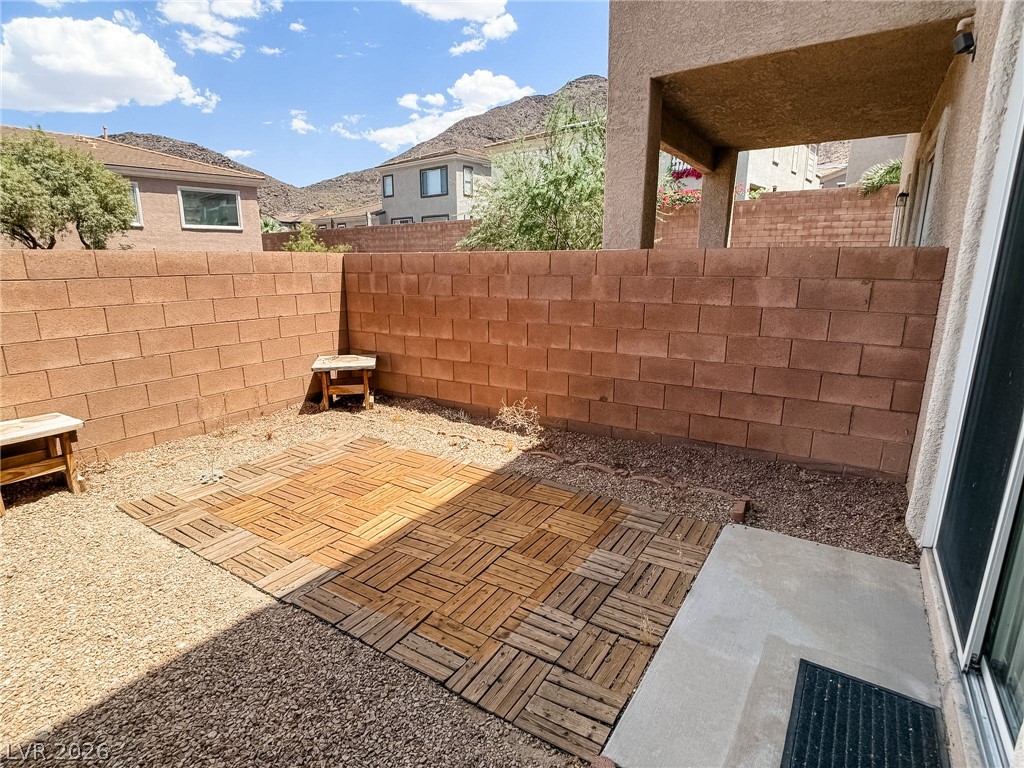 228 Positive Point Street Henderson, NV 89012 - Photo 23 of 27 A private, enclosed backyard retreat features a wooden patio amid gravel, offering a serene outdoor space.