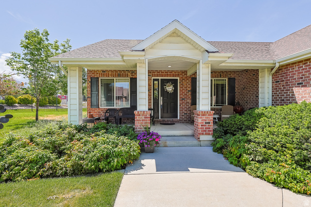 31 Village Square Road Centerville, UT 84014 - Photo 1 of 29 Brick facade home with a covered front porch, white columns, a dark entry door, and manicured shrubbery