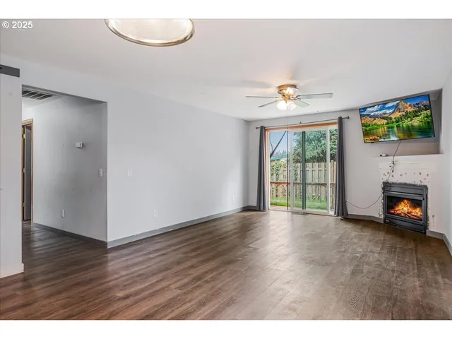 a view of an empty room with a window and wooden floor