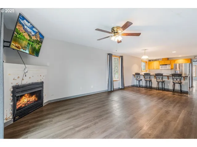 a view of an empty room with a fireplace and wooden floor