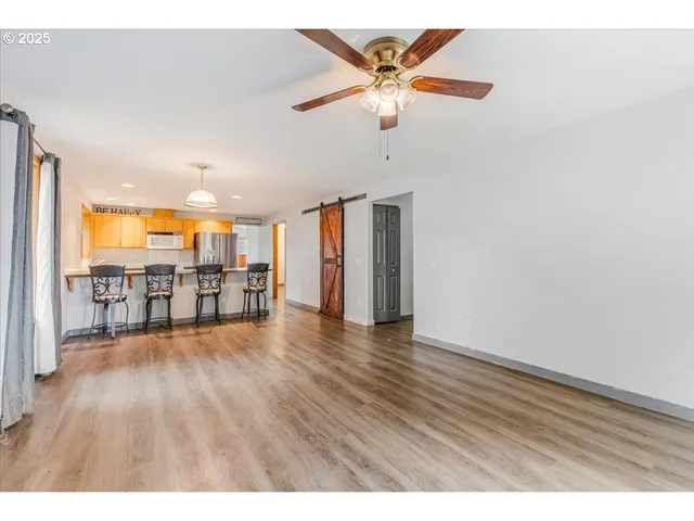 a view of an empty room with wooden floor and a ceiling fan
