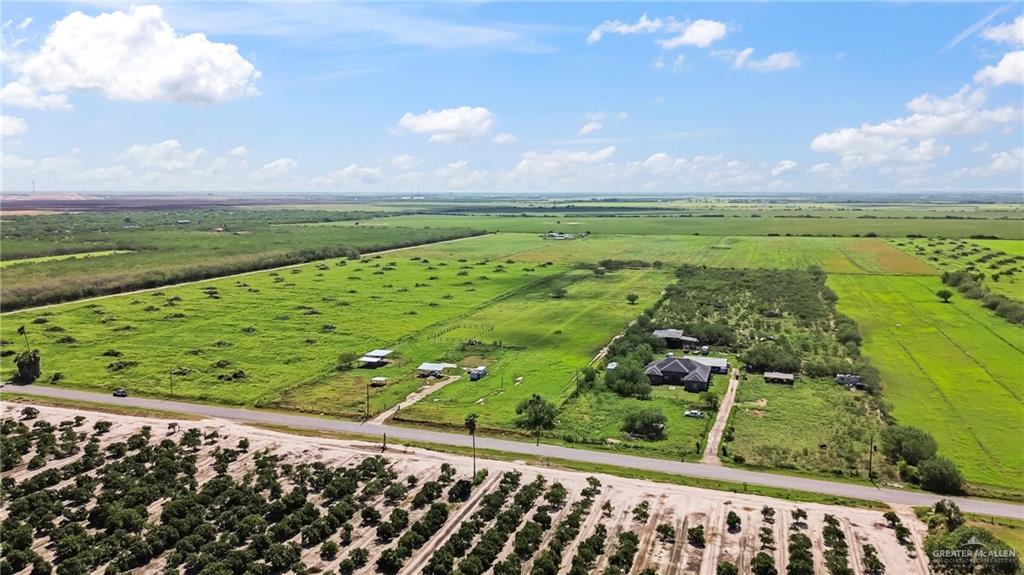 27870 North Western Road Mission, TX 78574 - Photo 4 of 8 Expansive agricultural property featuring a paved road frontage, established cultivated fields, and a residential structure with an asphalt shingle roof