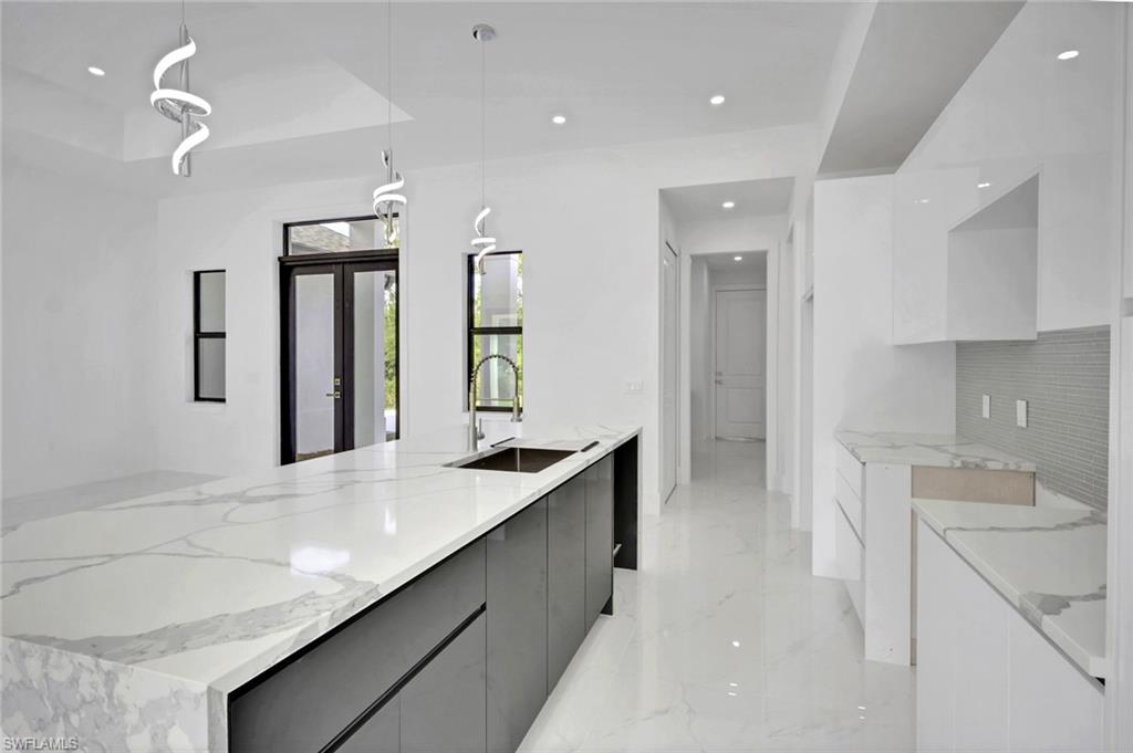 3780 6th Avenue Southeast Naples, FL 34117 - Photo 12 of 33 a kitchen with granite countertop a sink and white cabinets