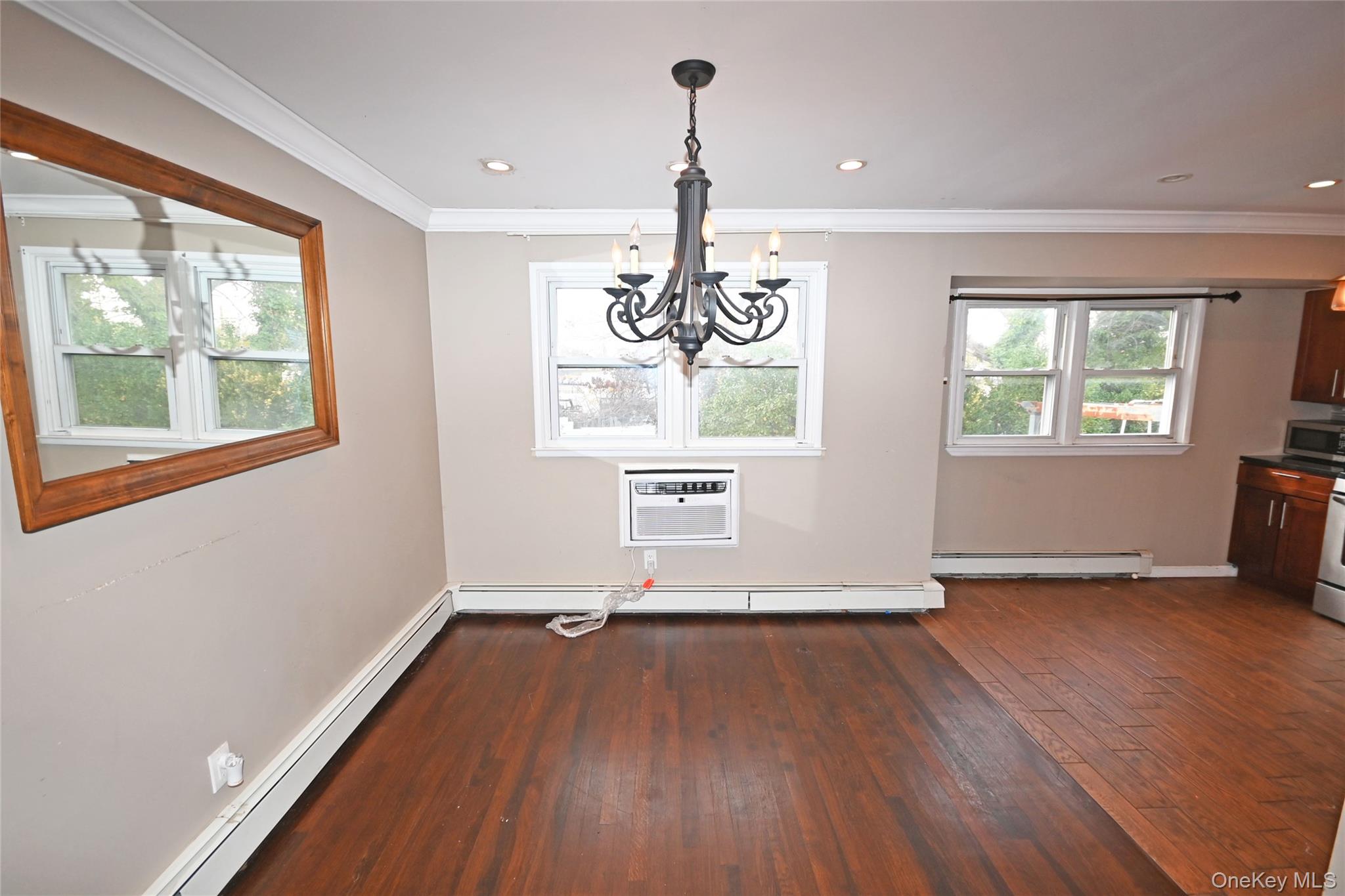 89 Osborne Road West Hempstead, NY 11552 - Photo 24 of 50 Unfurnished dining area with dark wood-type flooring, baseboard heating, crown molding, a chandelier, and recessed lighting