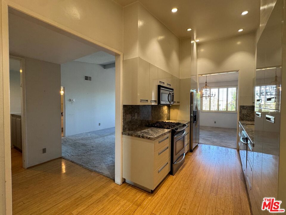 5100 Vía Dolce, Unit 305 Marina del Rey, CA 90292 - Photo 25 of 54 a kitchen with stainless steel appliances granite countertop a stove and a wooden floors