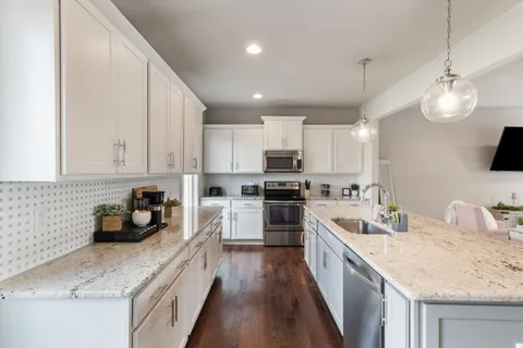a kitchen with granite countertop a sink a counter top space appliances and cabinets