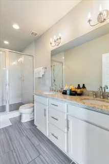 a bathroom with a granite countertop sink toilet a large mirror a shower and vanity