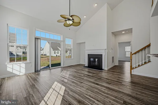a view of an empty room with wooden floor fireplace and a window