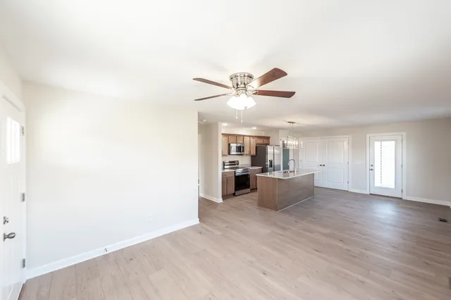 a view of living room with kitchen island stainless steel appliances wooden floor and window
