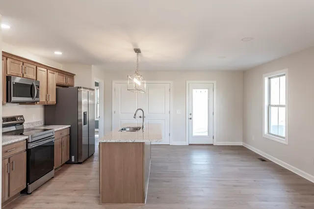 a view of a kitchen with a sink refrigerator and wooden floor