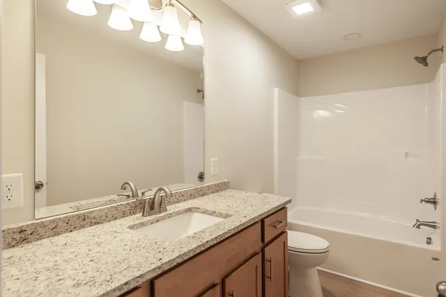 a bathroom with a granite countertop sink a toilet and bathtub