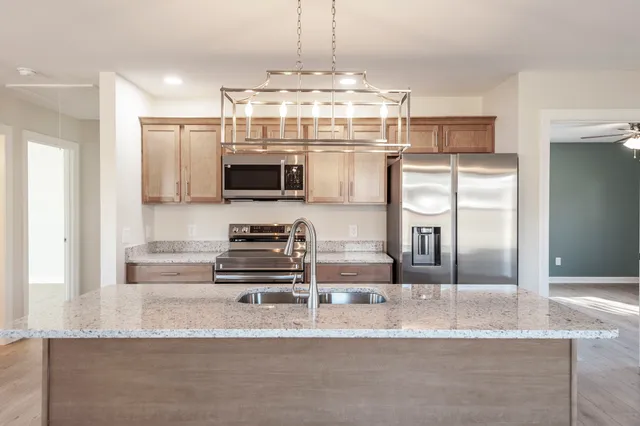 a kitchen with kitchen island granite countertop a refrigerator and microwave